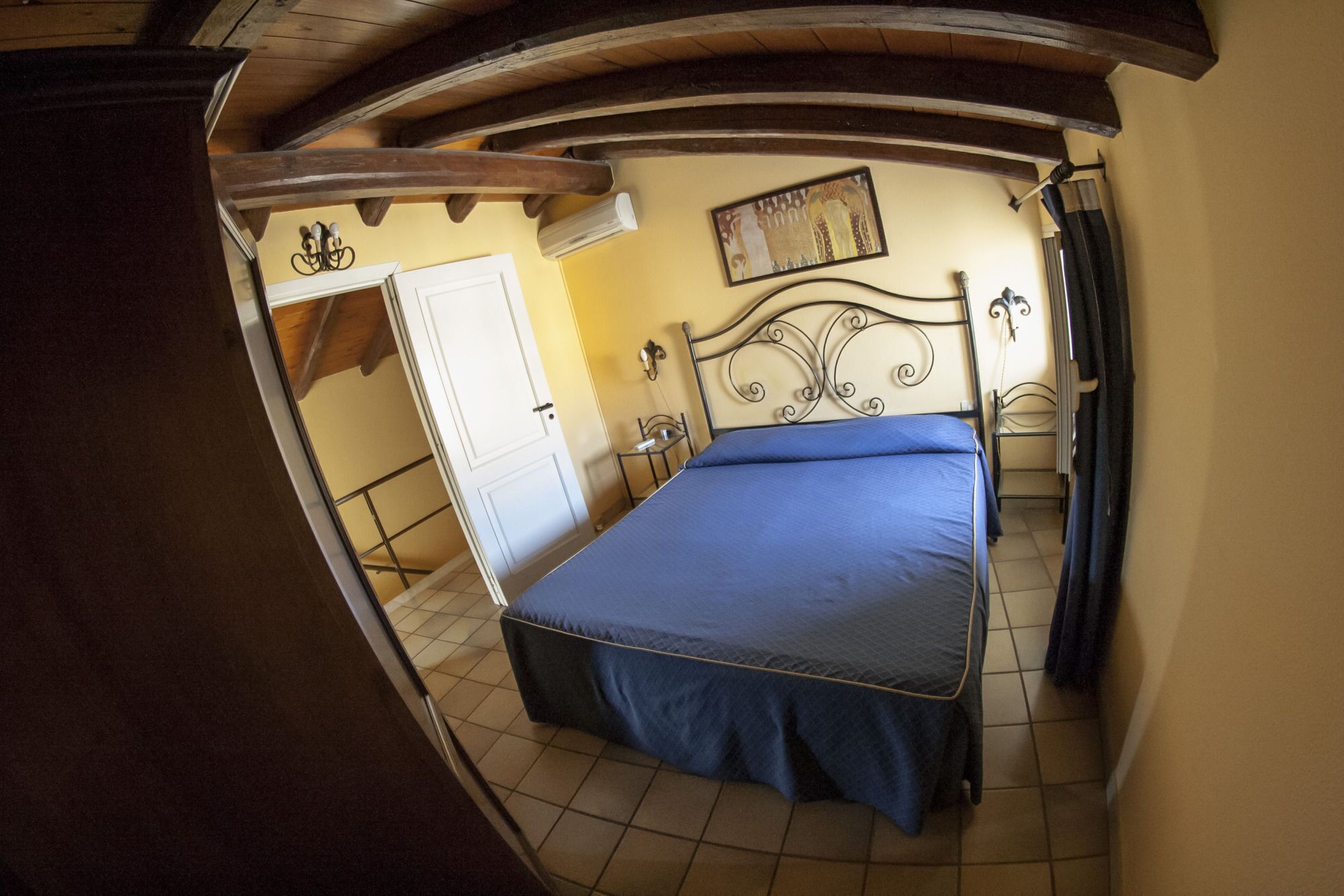 Une chambre à coucher avec un lit, une porte, une lampe fixée au mur et une fenêtre.
