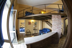 A compact living space with a kitchen area, a dining table, and a blue sofa. - Residence Dei Baroni (Syracuse)
