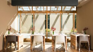 A dining area with a modern design, featuring a long table with chairs, a wooden ceiling, and large windows allowing natural light. - Feldmilla Design Hotel – Wellness & SPA (Campo Tures)