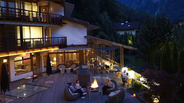 A two-story building with a patio area featuring outdoor seating and a fire pit. - Feldmilla Design Hotel – Wellness & SPA (Campo Tures)