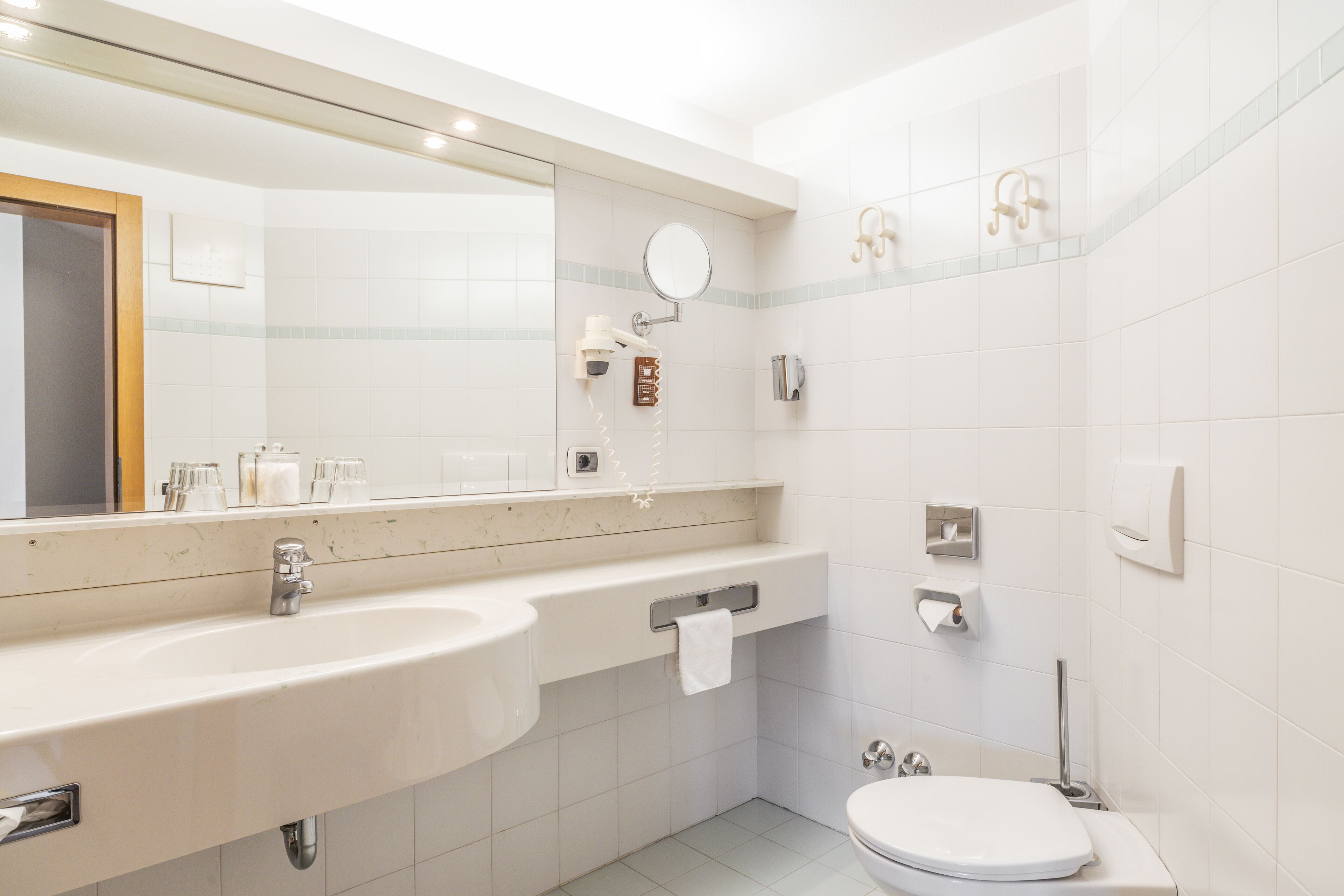 A modern bathroom with a large mirror, a sink, a toilet, and a shower area.