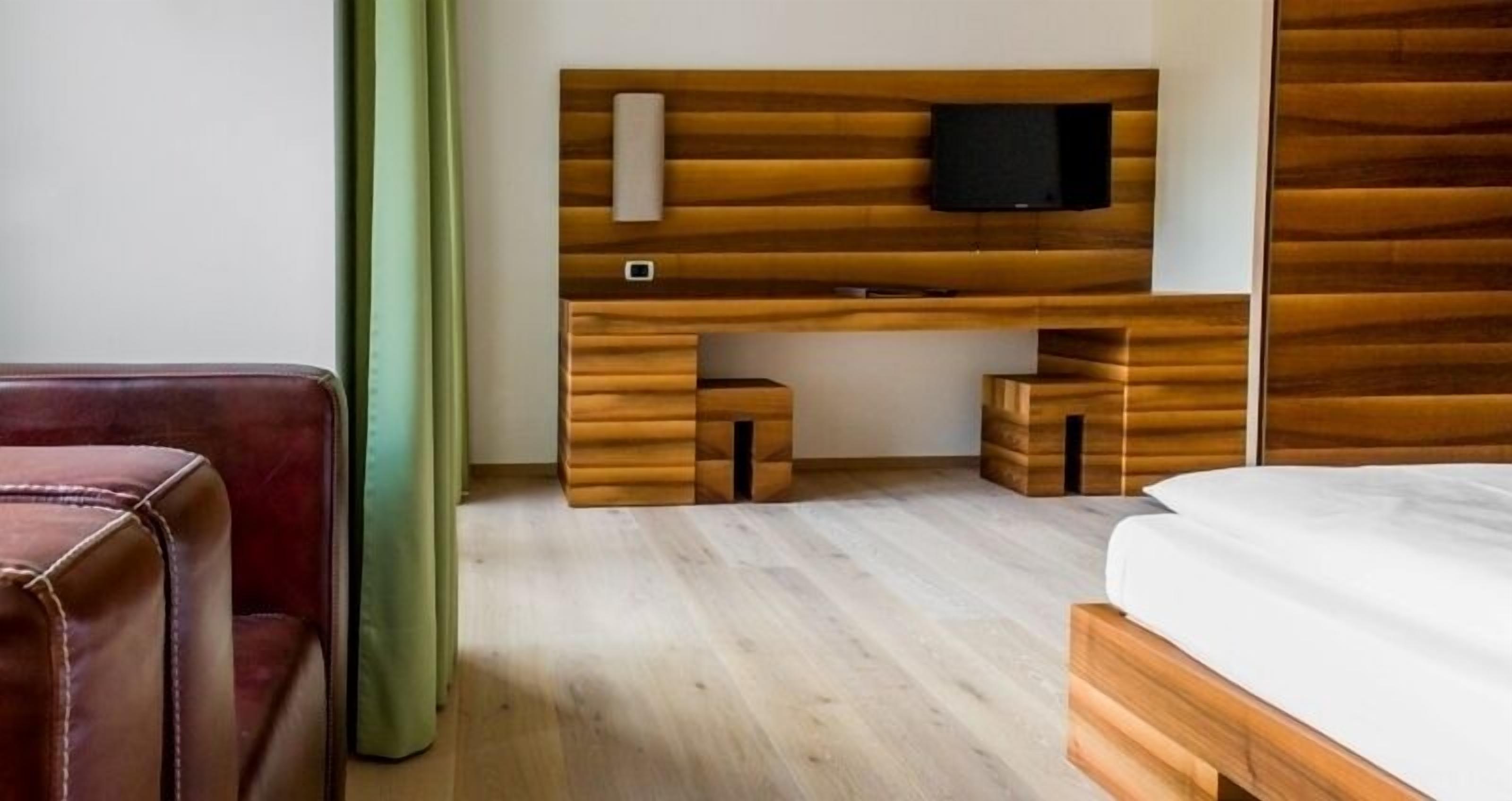 Una habitación de hotel con un escritorio de madera, televisor y cama.