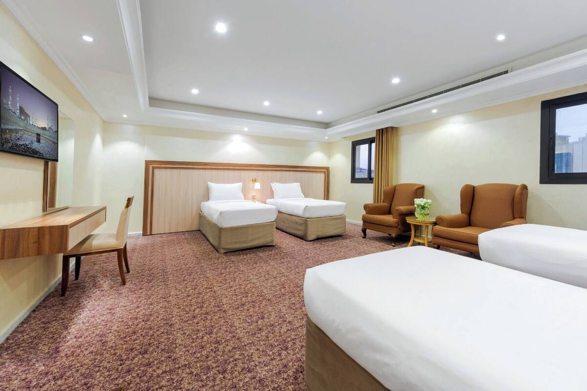 A hotel room with two beds, a desk, a chair, and a sofa.