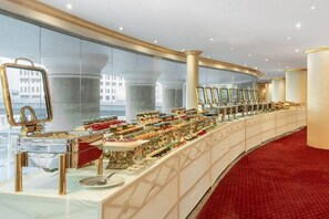 A buffet setup with various food items, a mirror, and a red carpeted floor. - Palestine Hotel Makkah (Makkah)