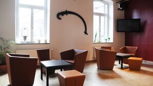 Un salón moderno con sillones de cuero, un televisor de pantalla plana y ventanas amplias.