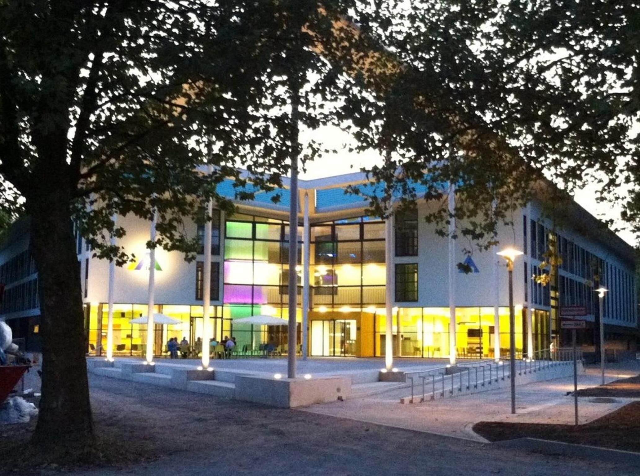 Een modern gebouw met een glazen gevel en een goed verlichte entree.