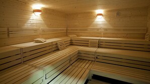 Een sauna met houten banken en twee wandlampen.