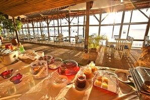 Zona de comedor frente a la playa, con mesas dispuestas para el desayuno, con vistas al mar.