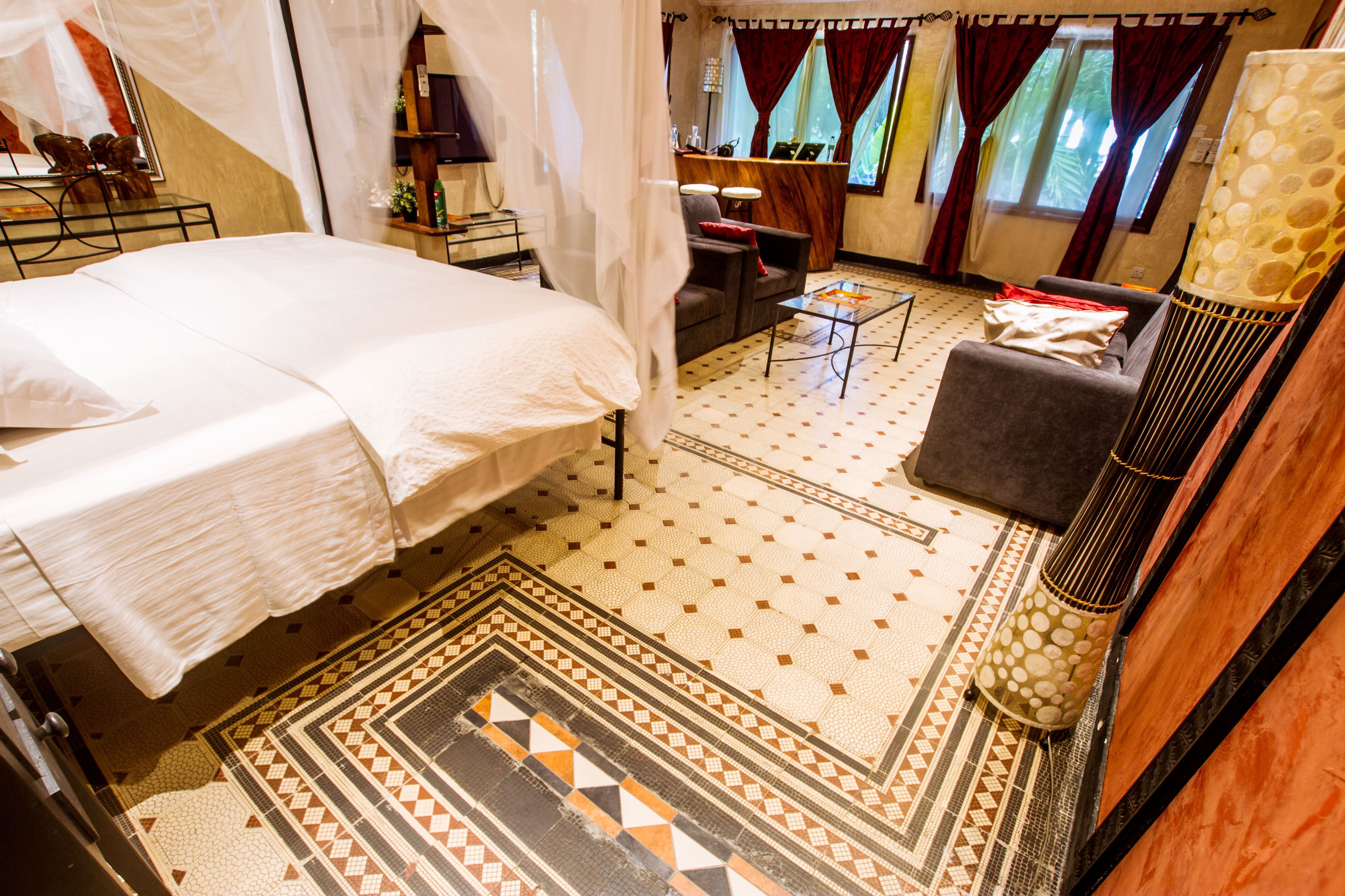 A hotel room with a bed, a desk, a chair, and a sofa.