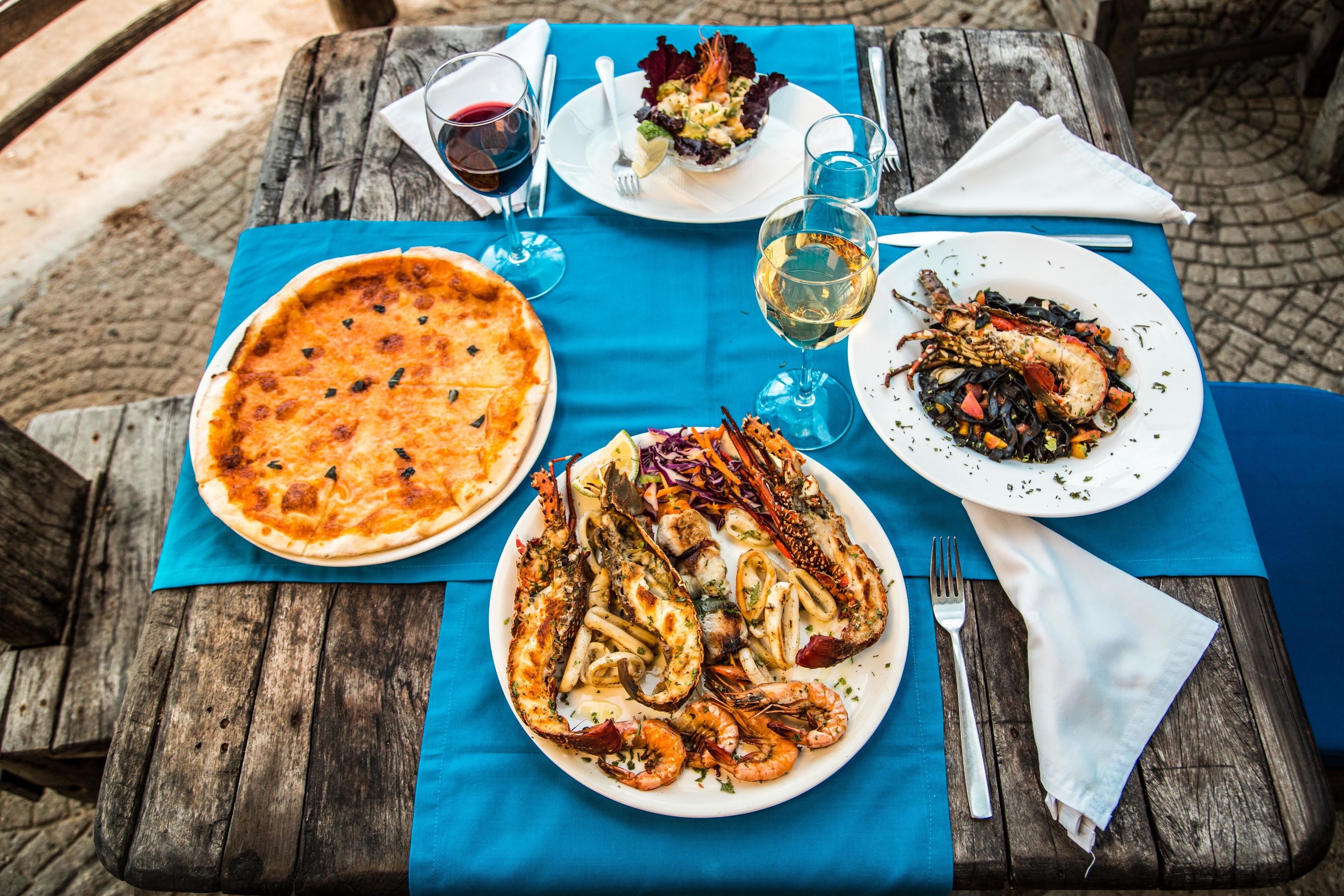 Une table avec une pizza, des fruits de mer et une salade.