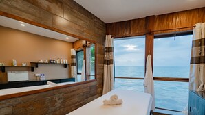 Een moderne badkamer met een houten wand, een grote spiegel, een witte wastafel en een handdoek op het nachtkastje.