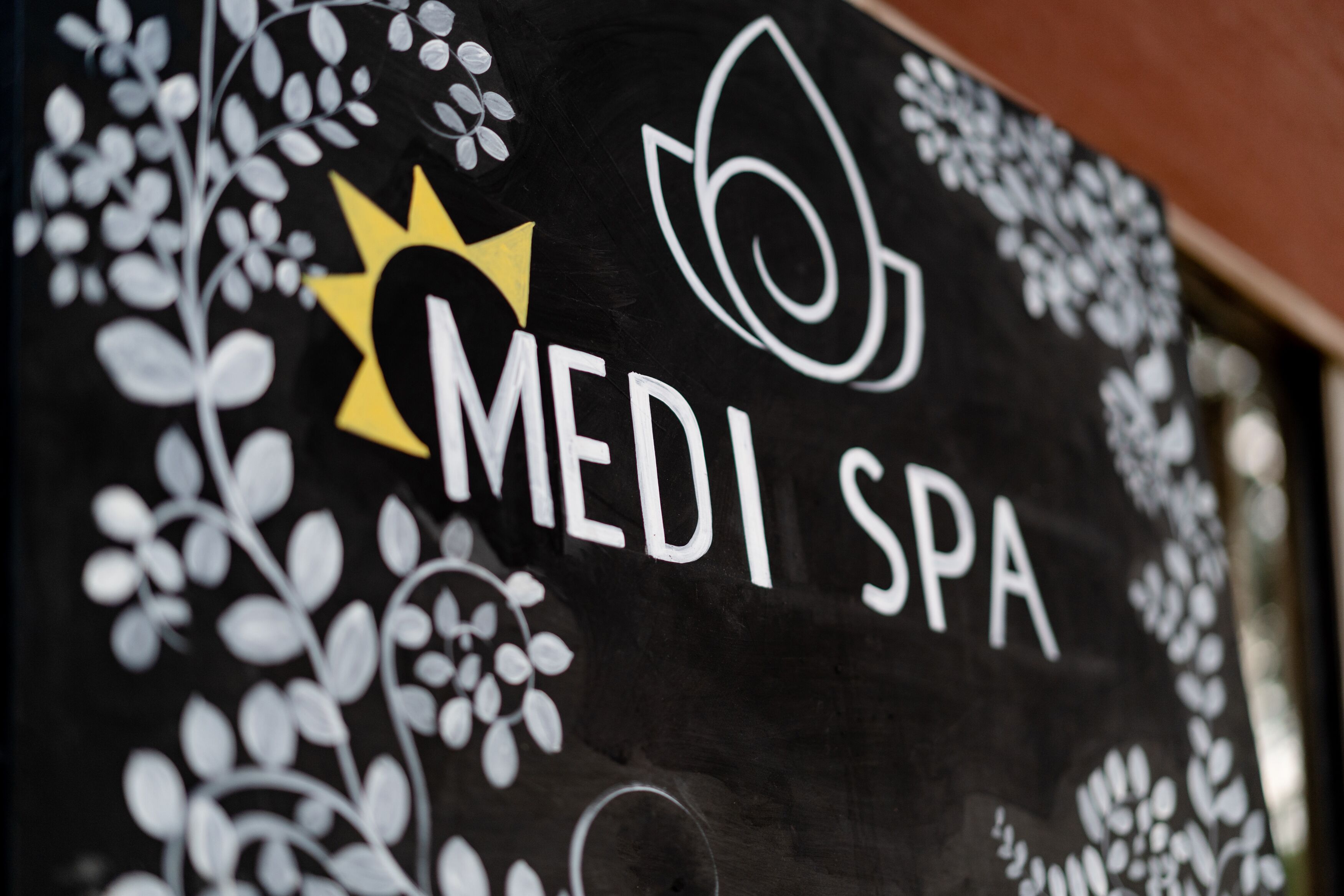Un letrero con el texto 'Medi Spa' y motivos florales decorativos.
