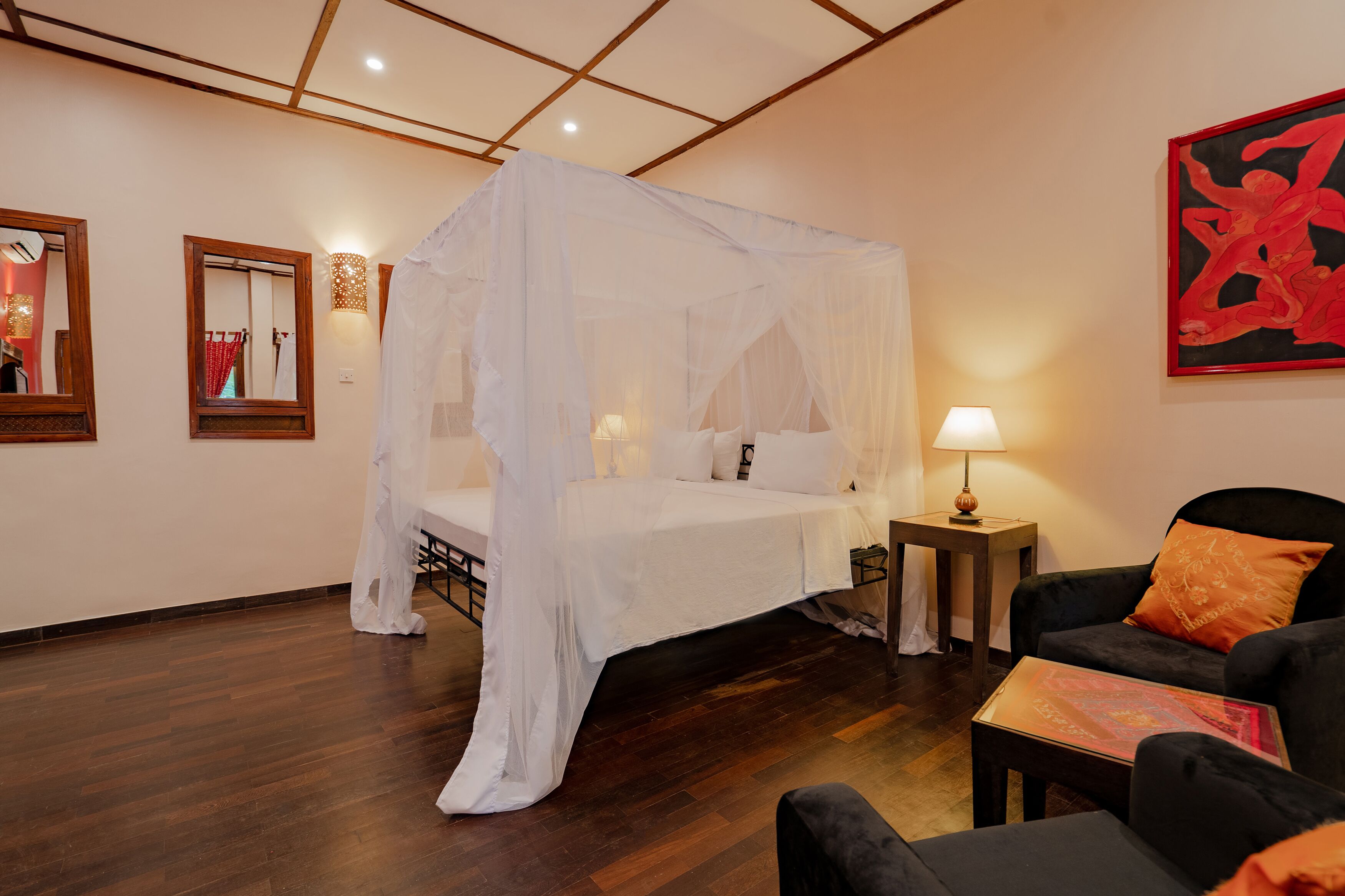 Une chambre à coucher avec un lit à baldaquin, une table de chevet avec une lampe, une chaise et un tableau au mur.