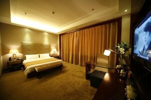 A hotel room with a large bed, bedside lamps, a TV, and a desk with a chair.