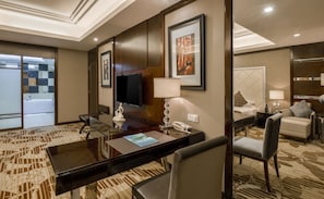 A hotel room with a large desk, a flat-screen TV, a lamp, a telephone, a sofa, and a bed. - Country Garden Phoenix Hotel Huiyang (Huizhou)