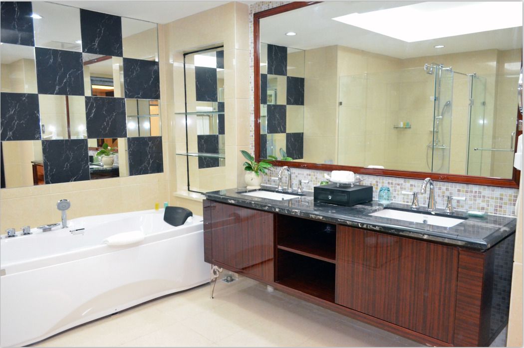 A modern bathroom with a large mirror, a bathtub, and a vanity with a sink.
