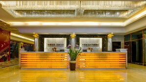 A hotel reception area with a modern design, featuring a marble reception desk, a large chandelier, and a potted plant. - Country Garden Phoenix Hotel Huiyang (Huizhou)