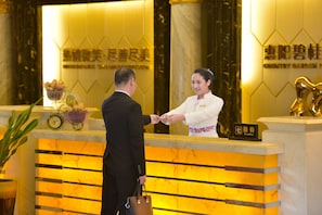 A hotel reception desk with a reception area, a clock, and a sign indicating the reception. - Country Garden Phoenix Hotel Huiyang (Huizhou)