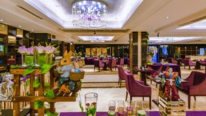 A spacious restaurant with multiple dining areas, elegant chandeliers, and a variety of table settings including purple tablecloths and glassware. - Country Garden Phoenix Hotel Huiyang (Huizhou)