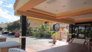 Ein Hotel Eingang mit einem Schild für 'Hawaiian Inn', einem überdachten Gang und einem Parkplatz mit Autos.