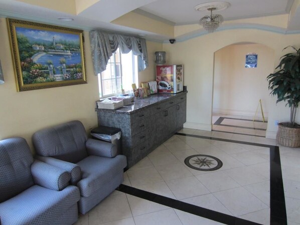 A living room with a sofa, a coffee machine, and a painting on the wall.