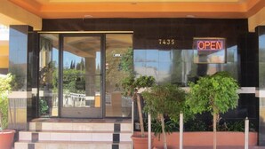 Ein Hotel Eingang mit Glastür, einem Schild mit der Zimmernummer 7435 und einem Schild mit der Aufschrift 'OPEN'.