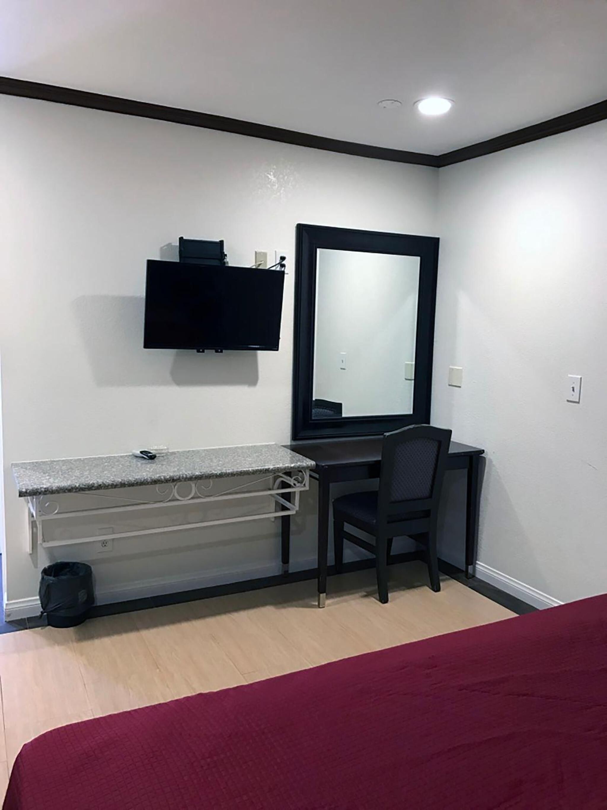 A small, clean room with a desk, chair, and a large mirror.