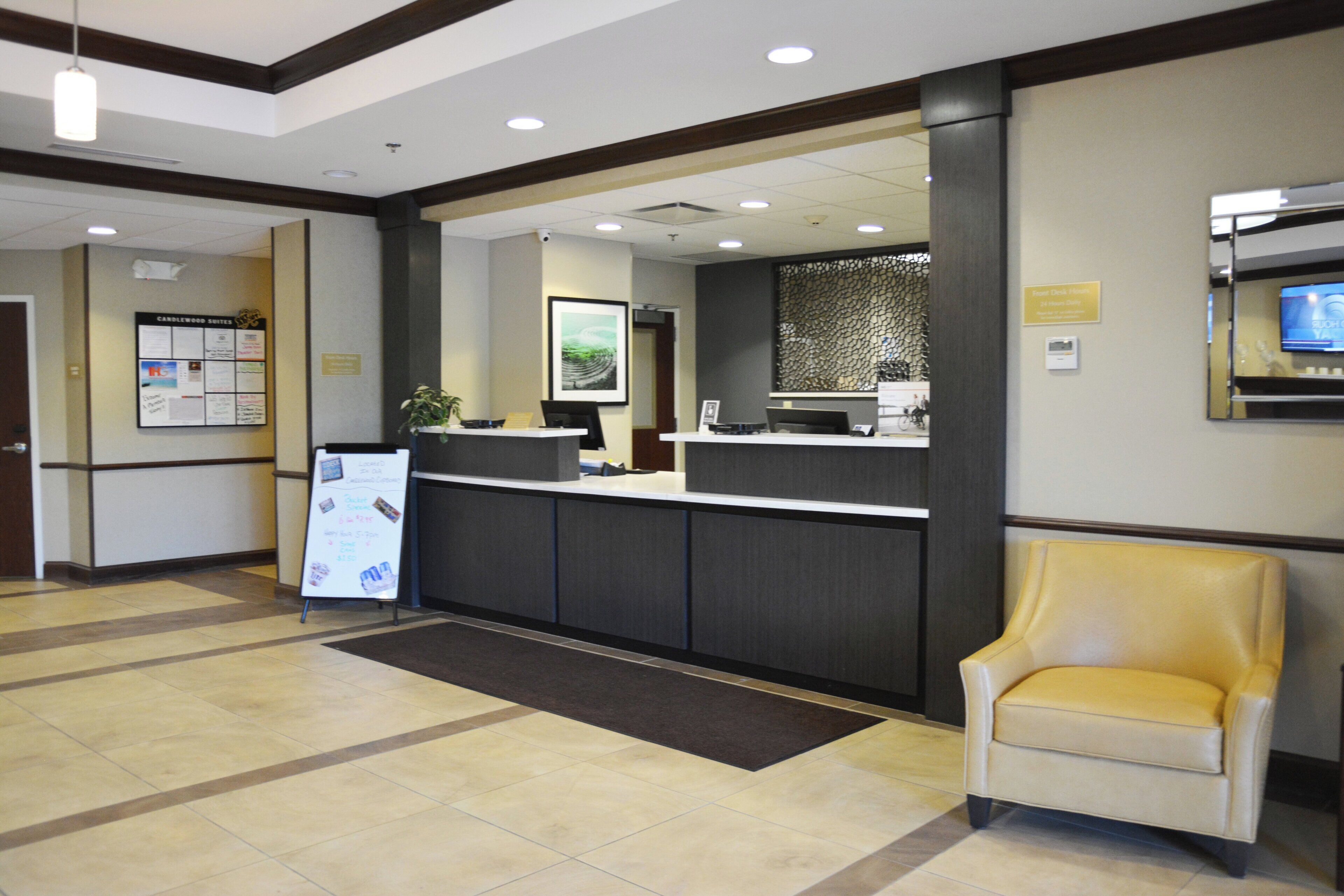 A reception area with a reception desk, a waiting area with a chair, and a wall-mounted television.