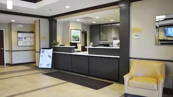 A reception area with a reception desk, a waiting area with a chair, and a wall-mounted television.