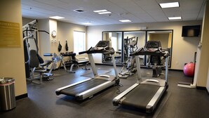 Une salle de sport équipée de tapis de course, de vélos elliptiques et de matériel de musculation.