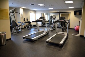 Une salle de sport équipée de tapis de course, de vélos elliptiques et de matériel de musculation.
