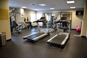 Un gimnasio con cintas de correr, elípticas y equipo de levantamiento de pesas.