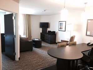 A hotel room with a round table, two armchairs, a sofa, a TV, and a desk with a telephone. - Candlewood Suites Youngstown West - Austintown by IHG (Austintown)