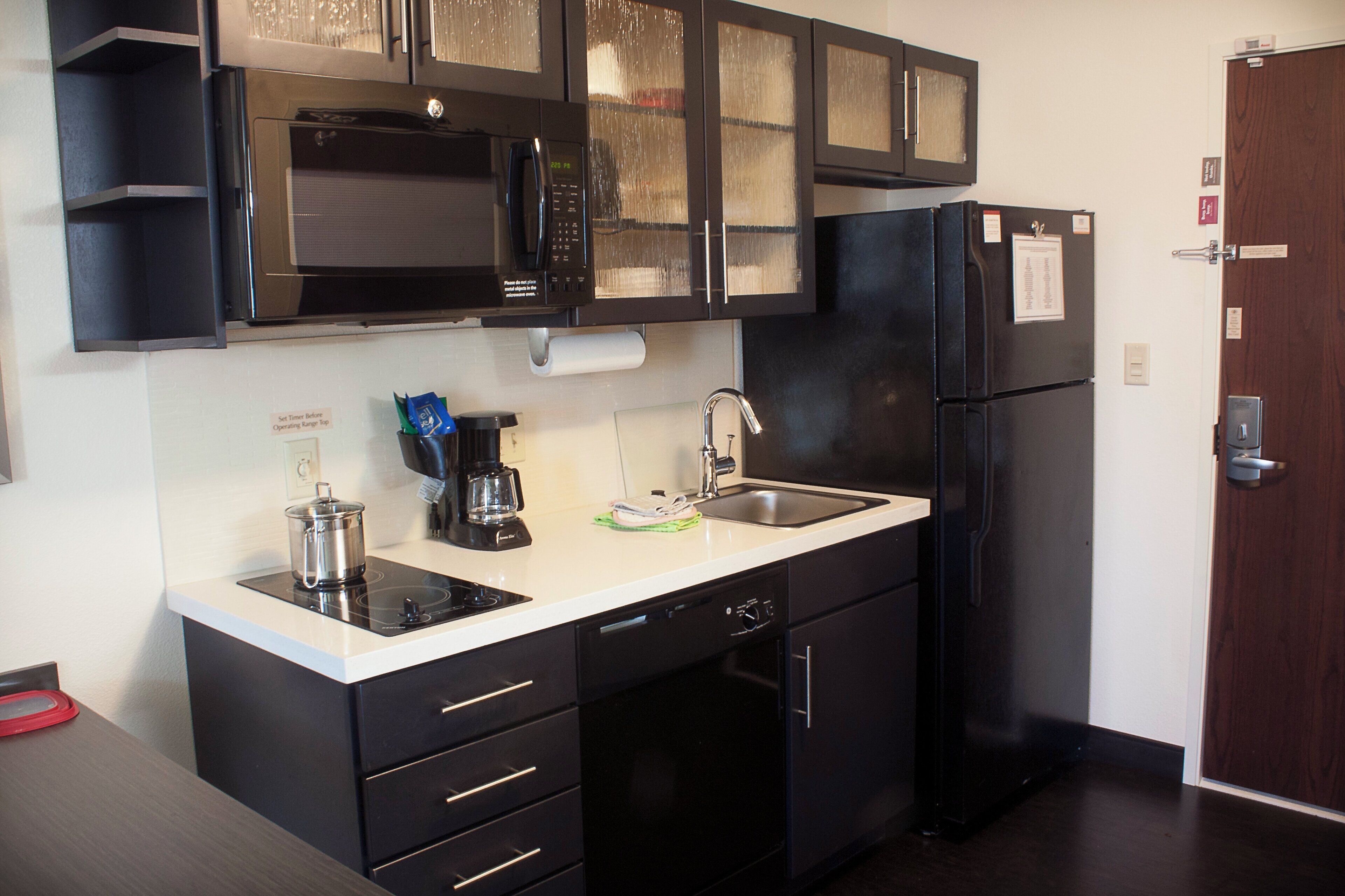 A compact kitchen with a microwave, coffee maker, sink, and a refrigerator.