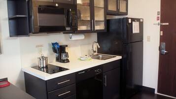 A compact kitchen with a microwave, coffee maker, sink, and a refrigerator.