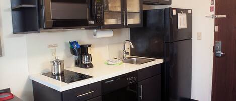 Una cocina compacta equipada con microondas, cafetera, lavaplatos y refrigerador.