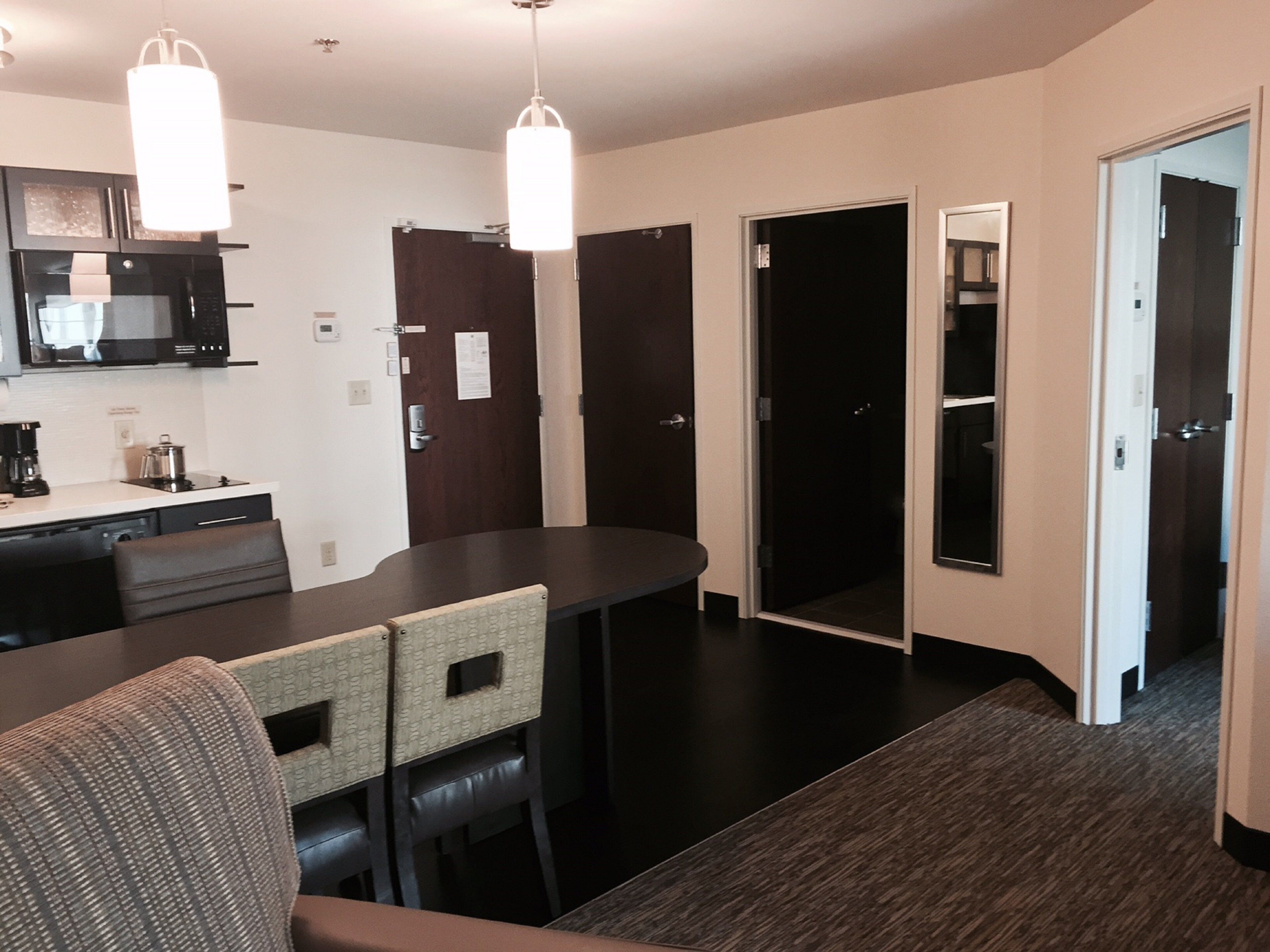 A modern kitchen with a microwave, coffee maker, and dining area with chairs and a table.