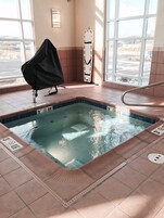 Una piscina con borde de azulejos, una silla de salvavidas y un ventanal con vistas al exterior.