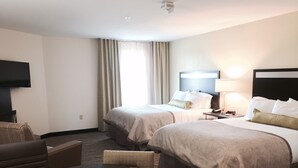 Une chambre d’hôtel avec deux lits, une télévision, un bureau et une chaise.