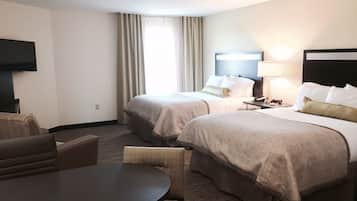 Habitación de hotel con dos camas, televisión, escritorio y silla.