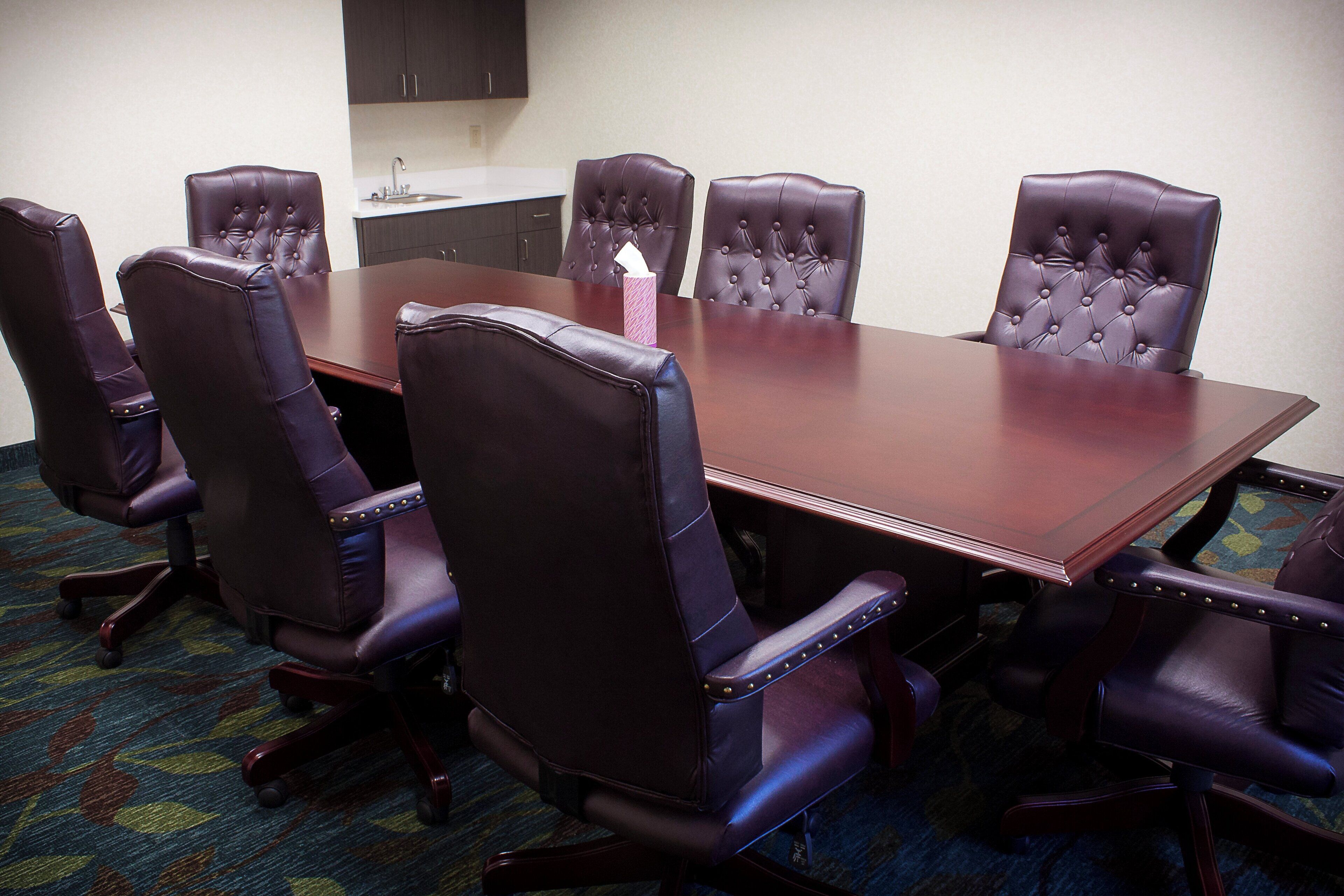 Une salle de conférence avec une grande table et six fauteuils en cuir.