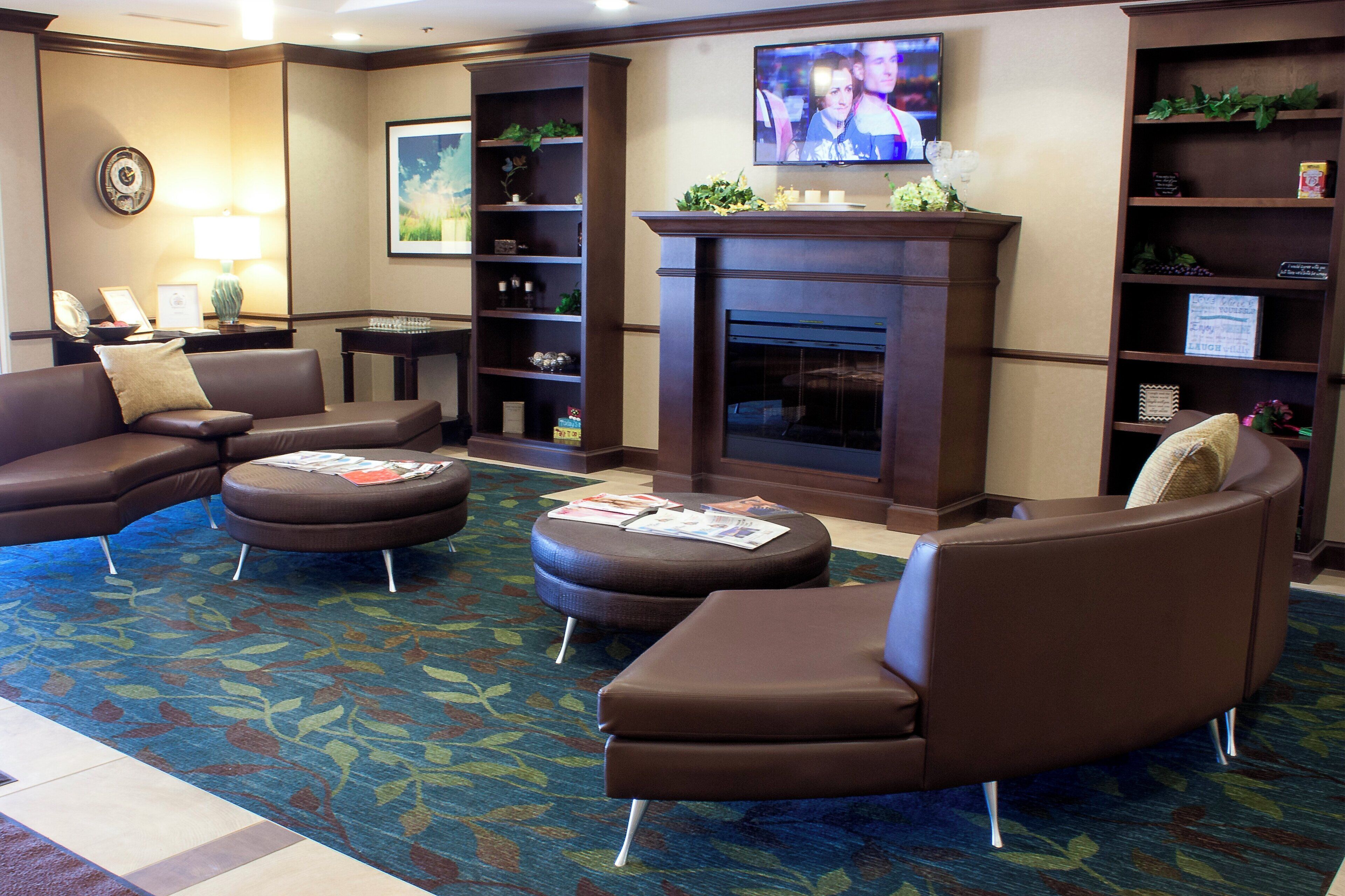 A hotel lobby with leather sofas, a fireplace, a television, and a bookshelf.