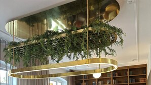 Un área de bar moderna con una isla central, taburetes y una estantería al fondo.
