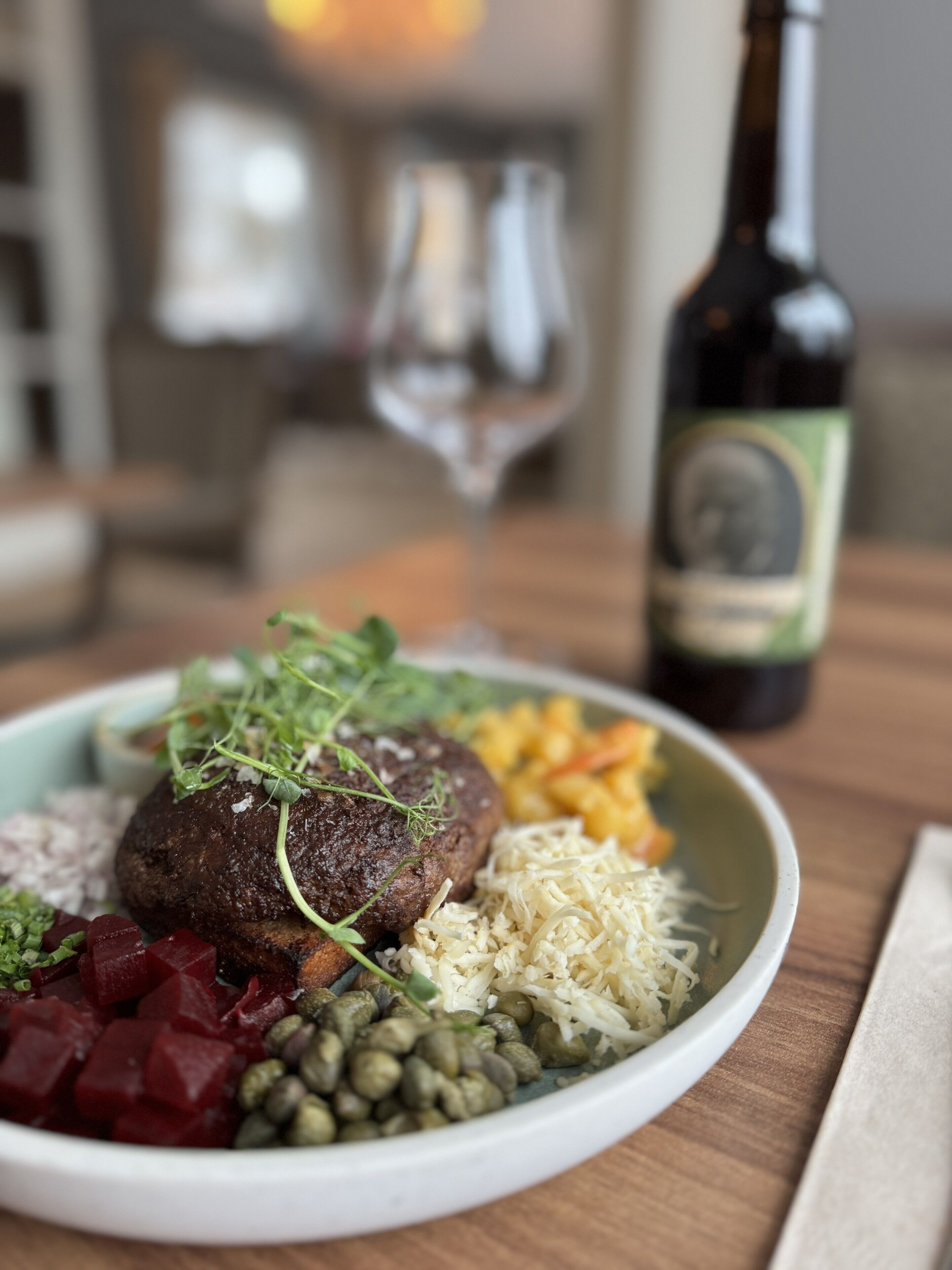 En tallerken mad med forskellige grøntsager og en flaske vin på et bord.