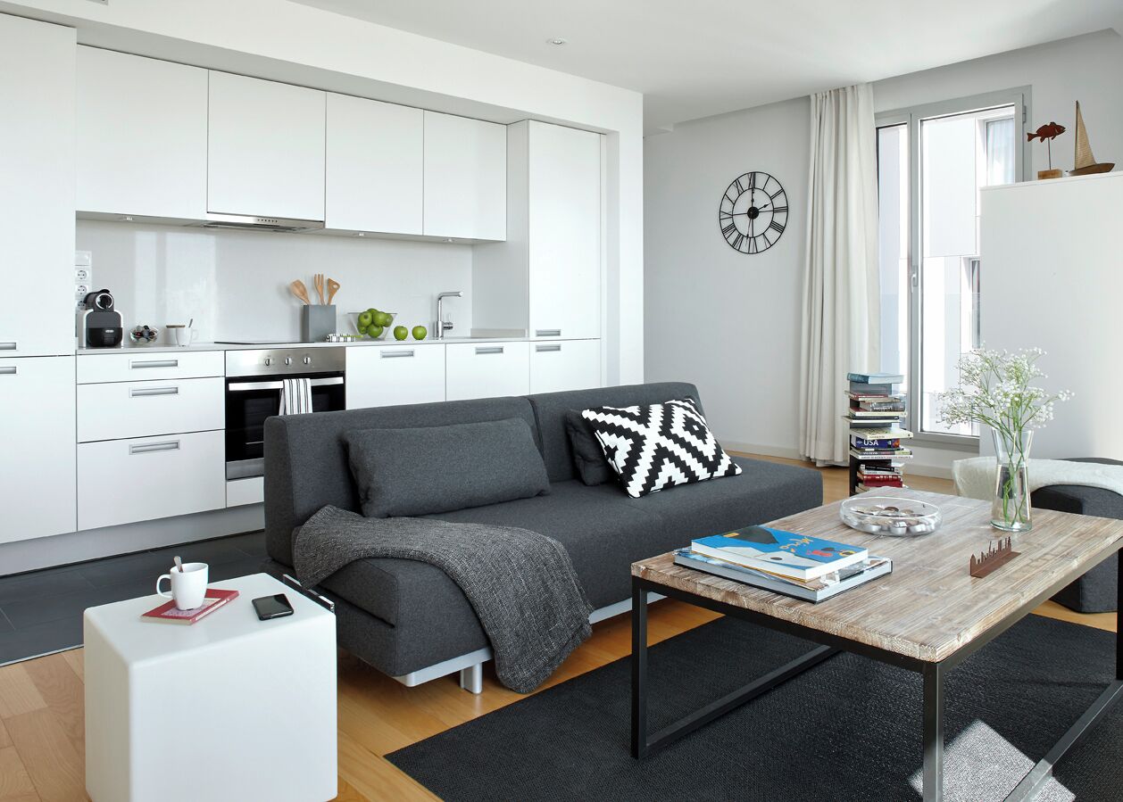 A modern living room with a grey sofa, a coffee table, and a bookshelf.
