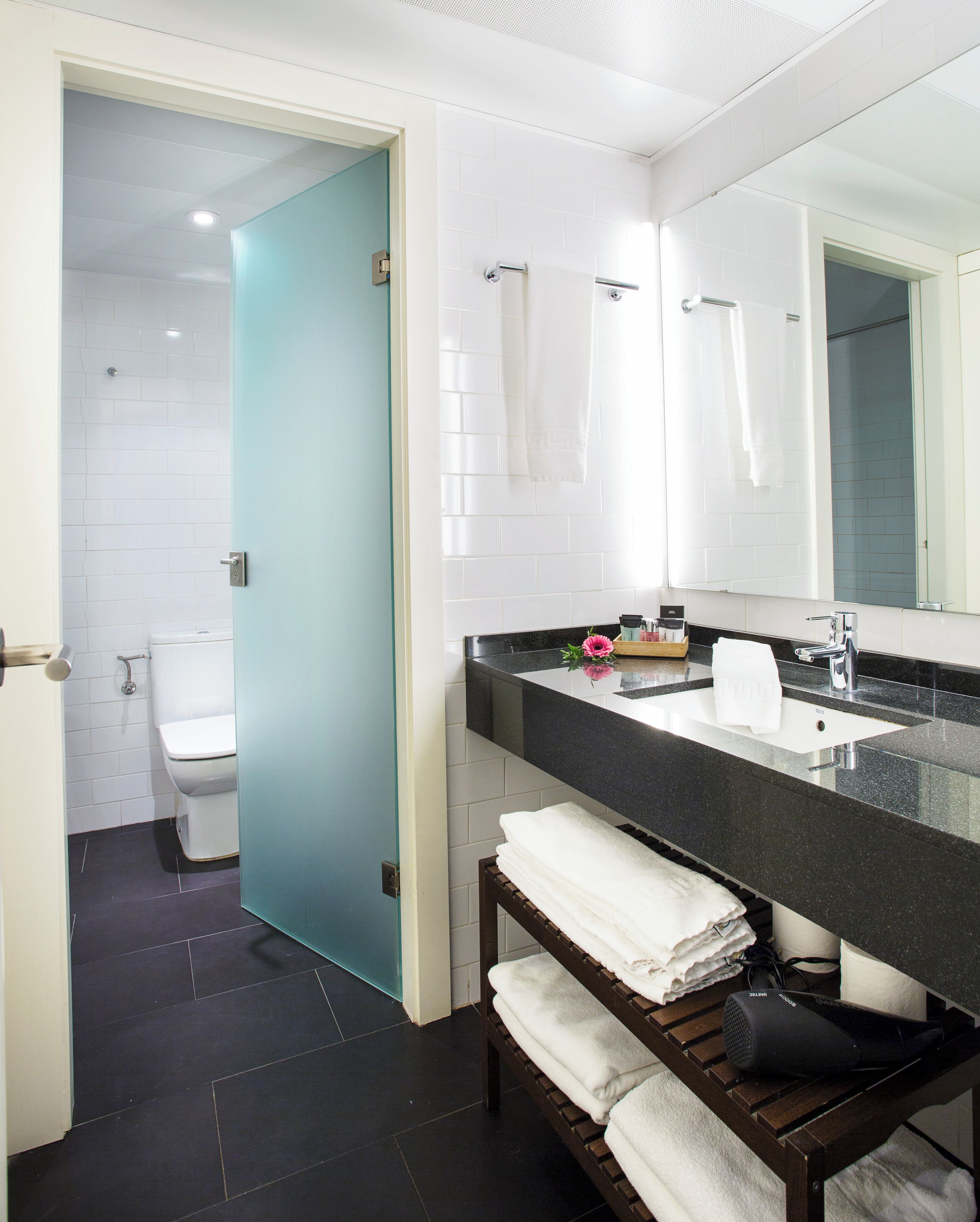 Ein modernes Badezimmer mit Toilette, Waschbecken und Spiegel.
