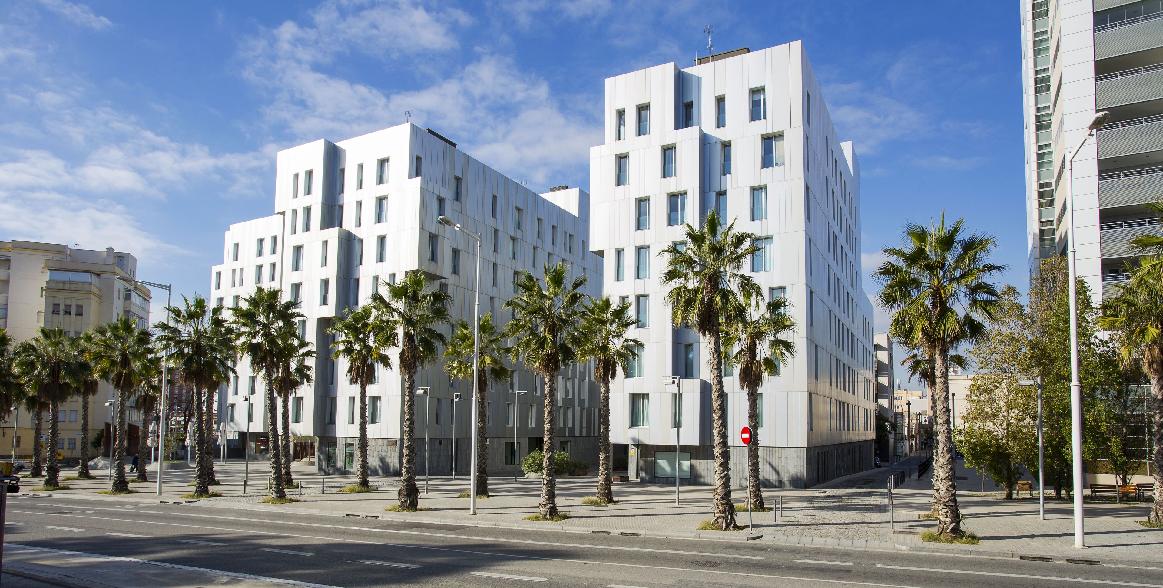A modern building with a white facade, multiple floors, and a no-entry sign.