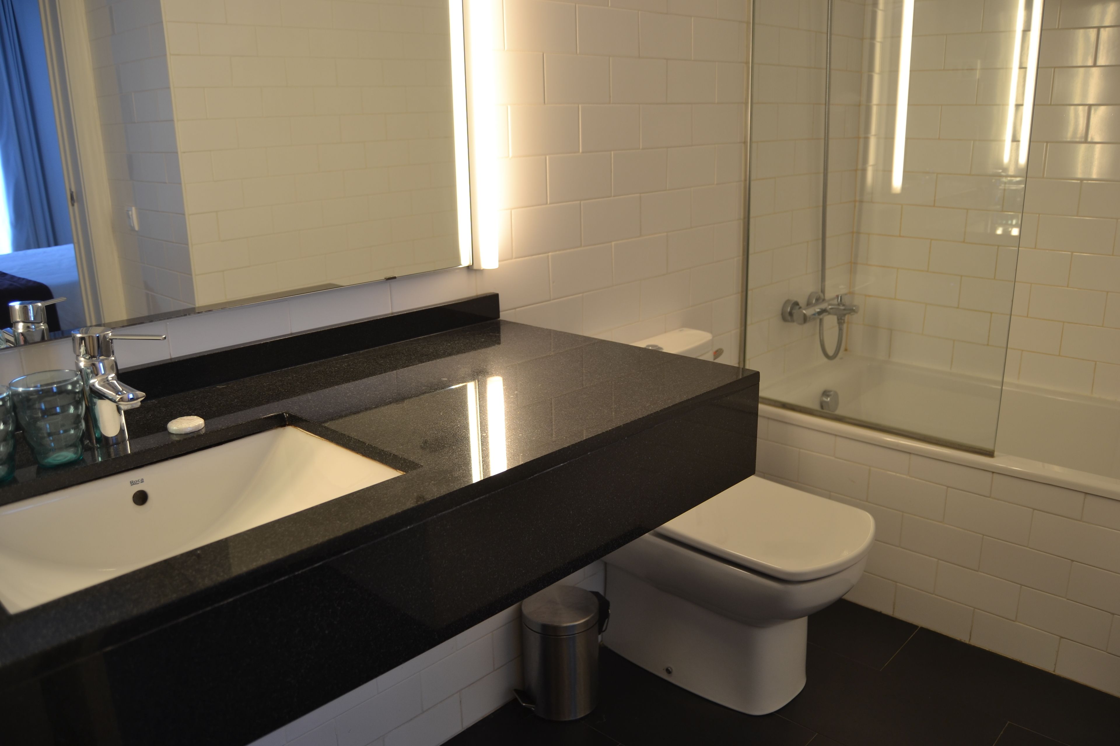 A bathroom with a black countertop sink, a white toilet, and a glass-enclosed shower.