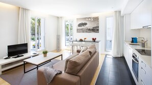 Ein modernes Wohnzimmer mit Flachbildfernseher, einer Couch, einem Couchtisch und einem Essbereich mit Tisch und Stühlen.