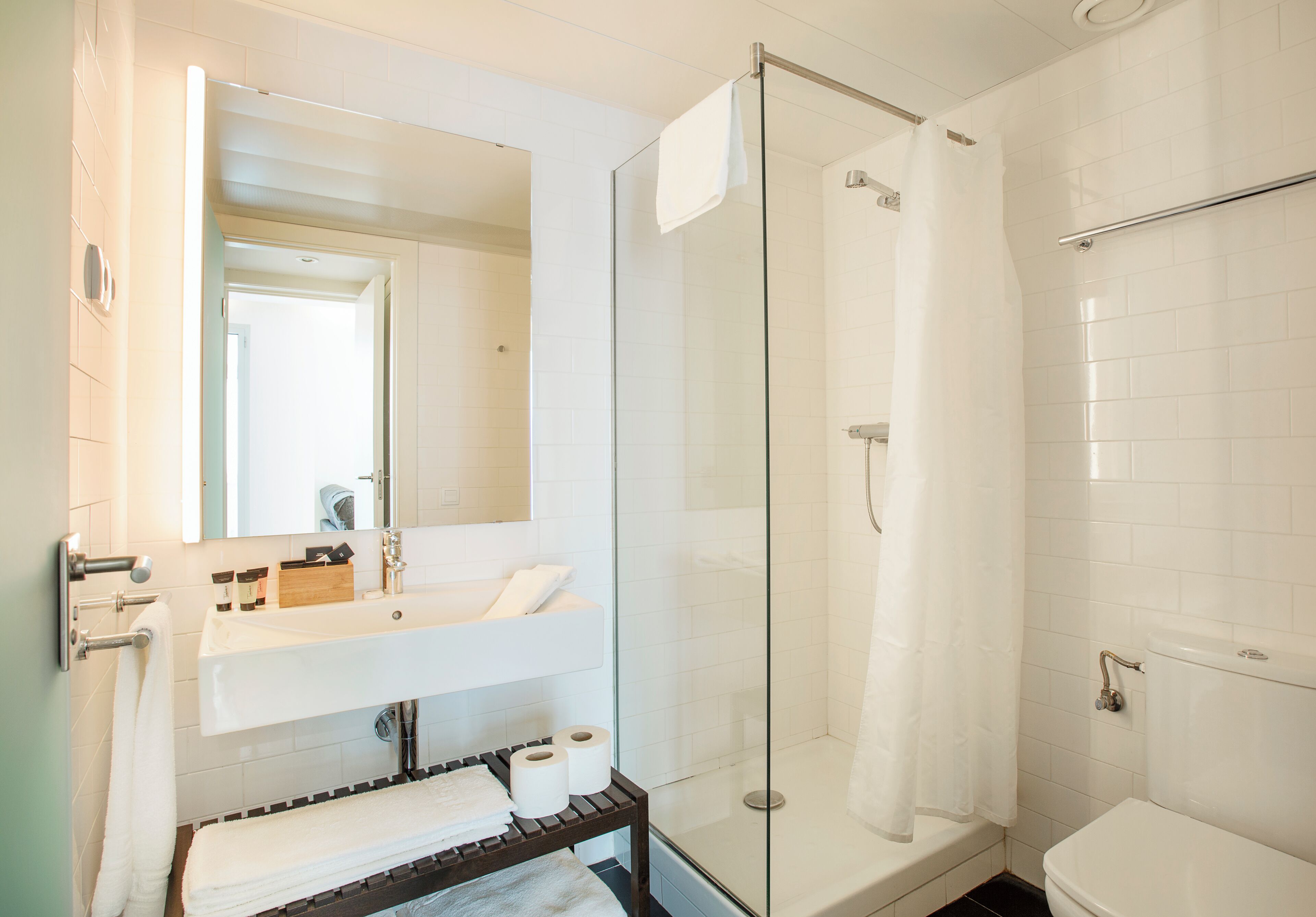 A modern bathroom with a glass-enclosed shower, a white sink with a mirror above it, and a toilet.